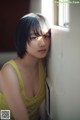 A woman leaning against a wall next to a window.