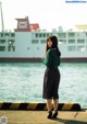 A woman standing on a pier next to a body of water.