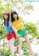 Two young women standing next to each other in front of a tree.