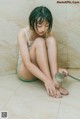 A woman sitting on the floor with a shower head.