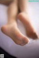 A close up of a person's bare feet on a bed.