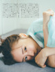 A woman laying on the floor with her head on her hands.