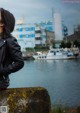 A woman in a leather jacket looking out over a body of water.