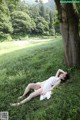 A woman in a white dress laying in the grass.