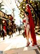 A woman in a red and white dress is walking down the street.