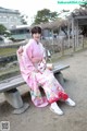 A woman in a pink kimono sitting on a bench.