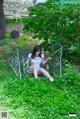 A woman sitting on a bench in the grass.