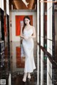 A woman in a white dress standing in a hallway.