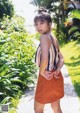 A woman in a striped top and orange skirt posing for a picture.