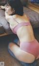 A woman in a pink bra and blue shorts sitting on a couch.