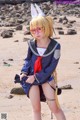 A woman in a sailor outfit is posing on the beach.