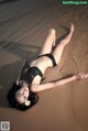 A woman in a black bikini laying on the sand.