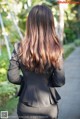 A woman in a black suit walking down a sidewalk.