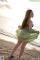 A woman in a green dress standing on a beach.