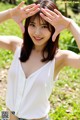 A woman in a white shirt and denim shorts posing for a picture.