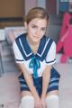 A woman in a blue and white uniform sitting on a bed.