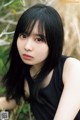 A woman with long black hair sitting in a field.