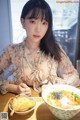 A woman sitting at a table with a bowl of food.